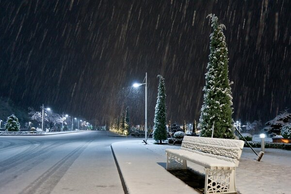 Strada notturna nella prima neve e nella luce delle lanterne