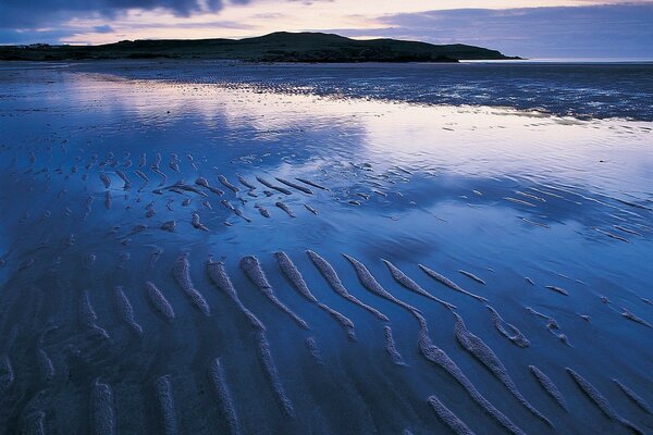 Reflection of the sunset in the low tide of the ocean