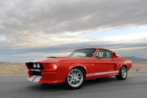 Mustang rouge sur la route sur fond de nuages