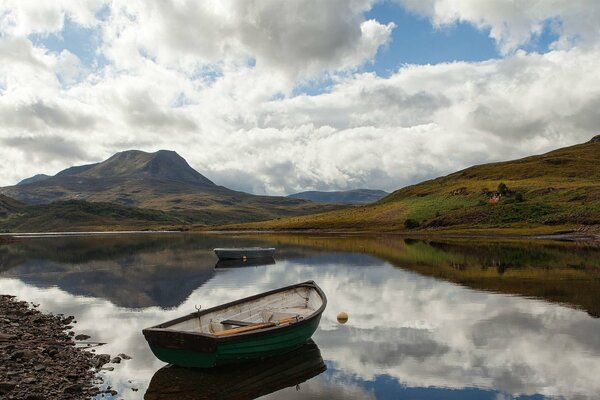 A boat on the lake. Clouds over the hills