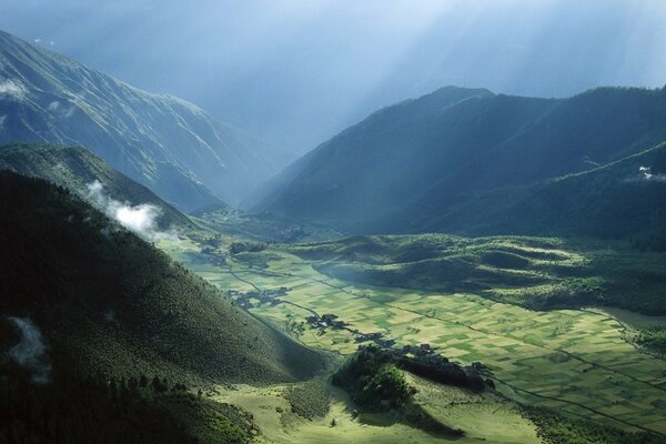 Die Sonne erhellt das Feld zwischen den Bergen