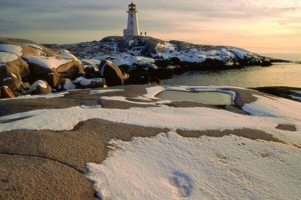 Sea. Lighthouse. Stones. Snow