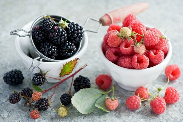 Raspberries and blackberries in bowls on the table