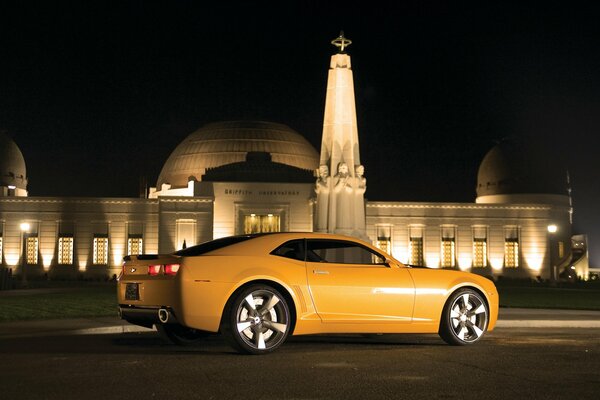 Automóvil Chevrolet color amarillo por la noche frente al edificio