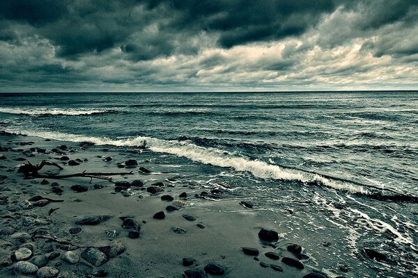 Plage sableuse. Ciel sombre et mer bleue