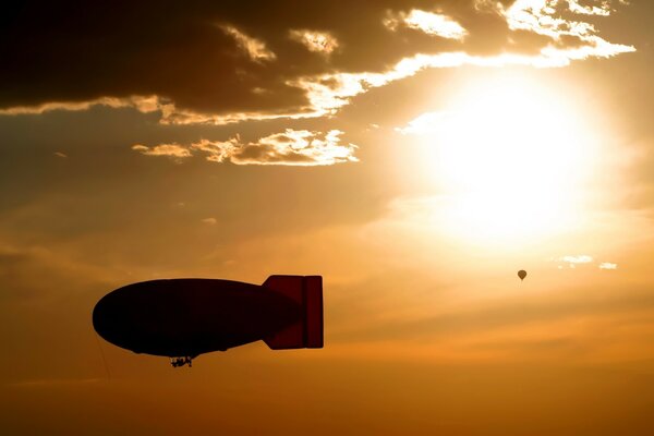 Luftschiff und Ballon am Himmel bei Sonnenuntergang