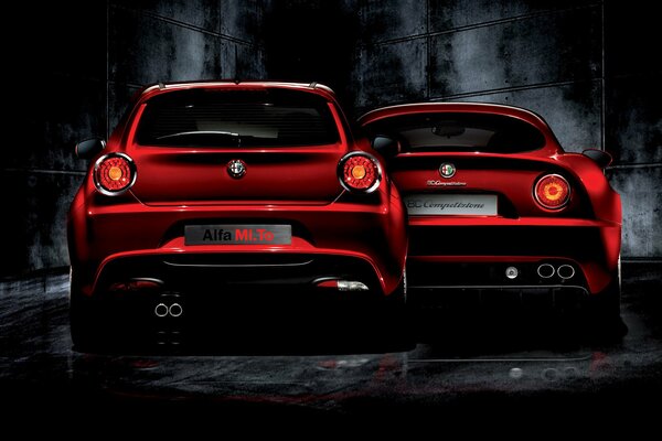 Deux alfa romeo rouges sur fond de mur noir sombre