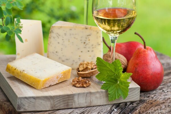 Rebanadas de queso en una tabla con vino blanco