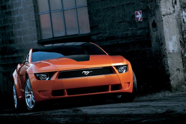 Foto de un Ford mustang giugiaro naranja en un callejón