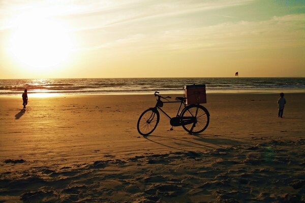 Una bicicleta de pie en la orilla arenosa del océano Índico contra el sol Poniente