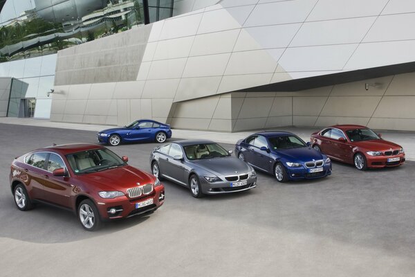 There are five multicolored BMWs in the parking lot. There are four in the foreground, and another one in the background