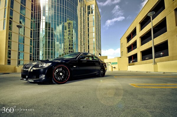 A black BMW is standing on the asphalt among the houses