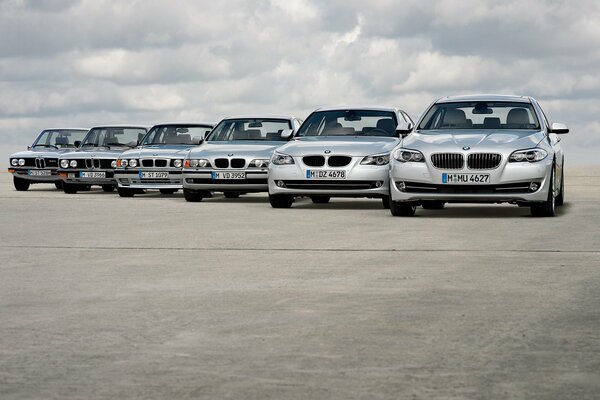 Seis bmw en la carretera en medio de un cielo nublado