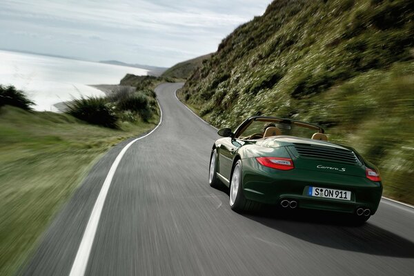 A dark green Porsche meows down the road at high speed