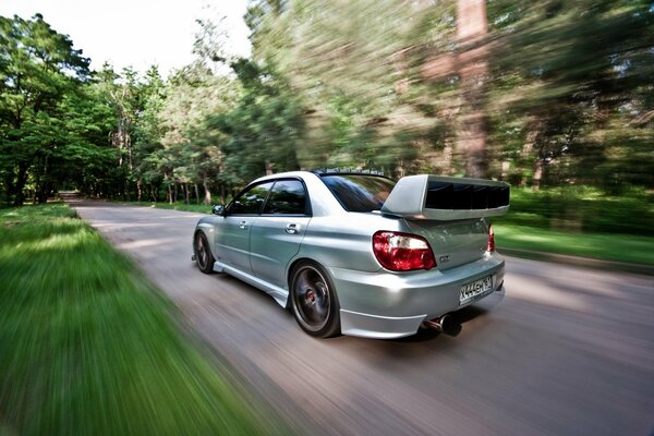 Fondo borroso de la carretera de campo con el coche Subaru