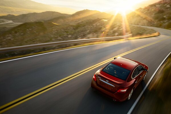 Nissan Maxima auf einer Bergserpentin. Sonnenuntergang