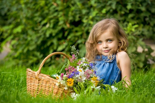 Ragazza con un cesto di fiori di prato sul prato verde