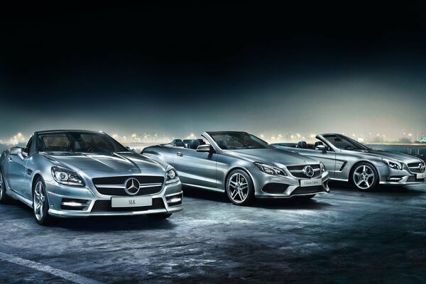 Three silver Mercedes convertibles on a dark background