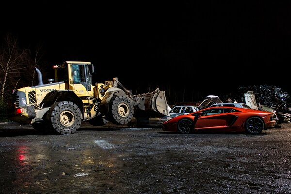 Bulldozer Volvo por la noche con Lamborghini naranja