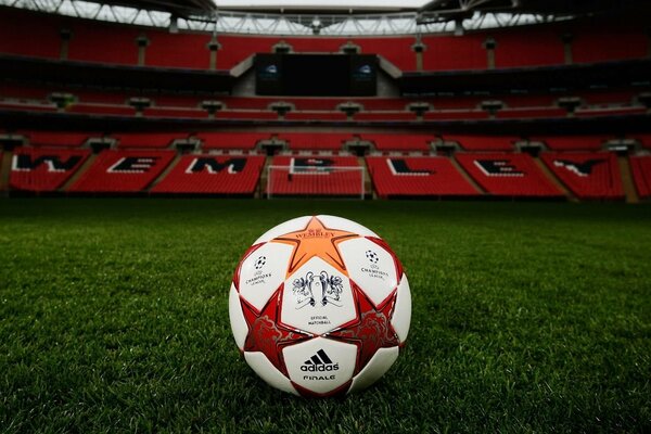 A ball on a green field in an empty stadium