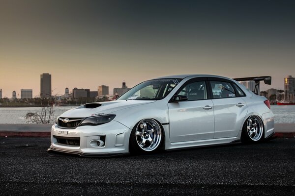 White Japanese-made Subaru Impreza car on the background of the city