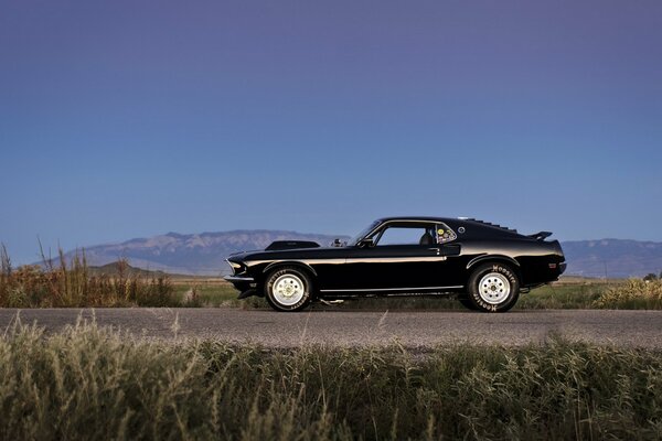 Un ford mustang negro monta en la carretera