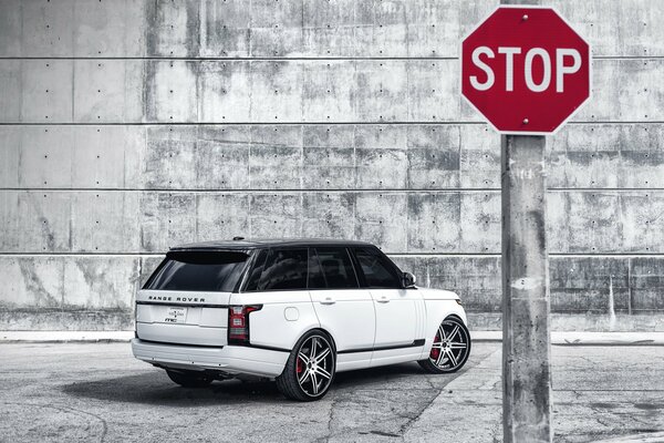 Señal de Stop en el Won de un range Rover blanco y una pared de piedra