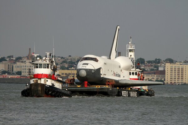 In the photo, a tugboat transports an airplane