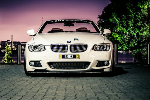 A white car is parked on the cobblestones