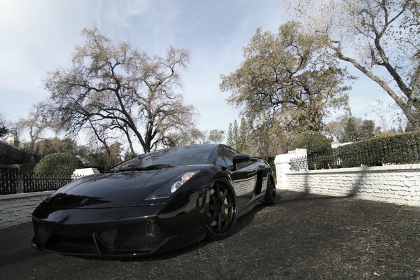 Czarny, przyciemniany samochód-lamborghini gallardo, lp540-4, na tle błękitnego nieba