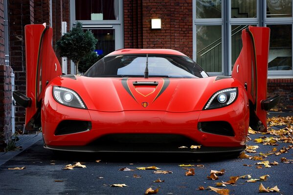 Coche rojo en el fondo de las hojas amarillas en la casa