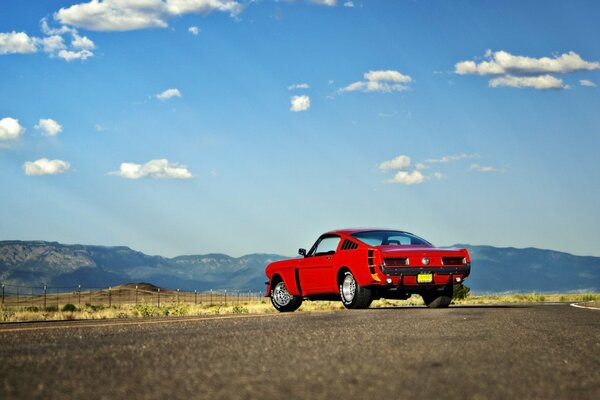 Czerwony mustang ford na pustynnej drodze