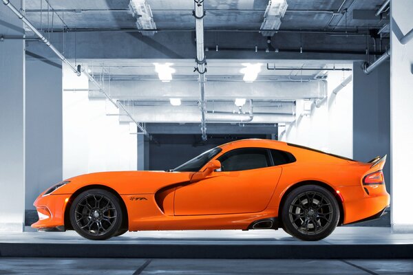 Orange Dodge in the underground parking lot, side view