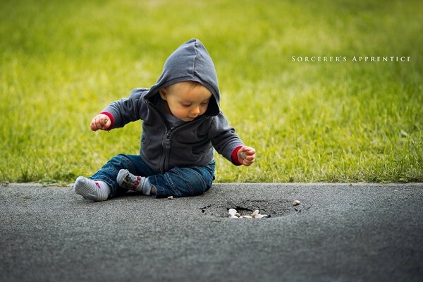 Ein kleiner Junge sitzt auf dem Asphalt