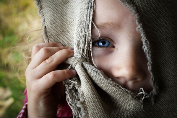 Fille regarde à travers la fente dans la toile de jute