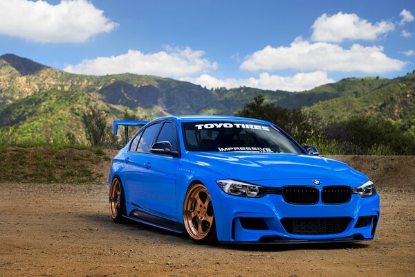 BMW serie 3 en azul sobre las montañas