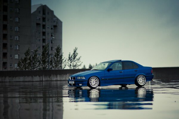 Auto blu BMW M3 E36 su asfalto bagnato