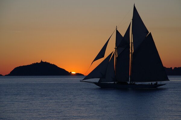 Yacht with a sailboat at sunset at sea