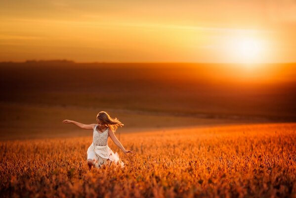 A girl in a wheat field against the background of sunset