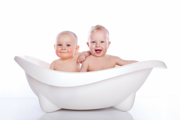 Two babies bathe in a small tub