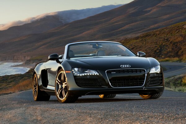 Audi R8 convertibile nera sullo sfondo delle montagne