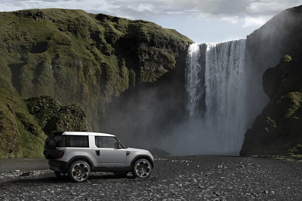 Land Rover-Auto auf dem Hintergrund eines schönen Wasserfalls