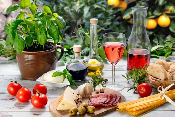 A glass of wine on the table with sausages, cheese, olives