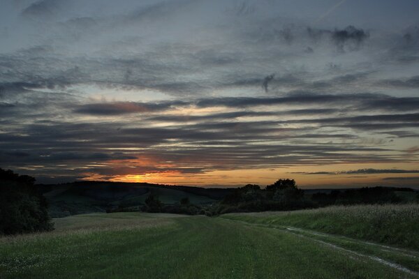 The road leading to the hills. Sunset with clouds