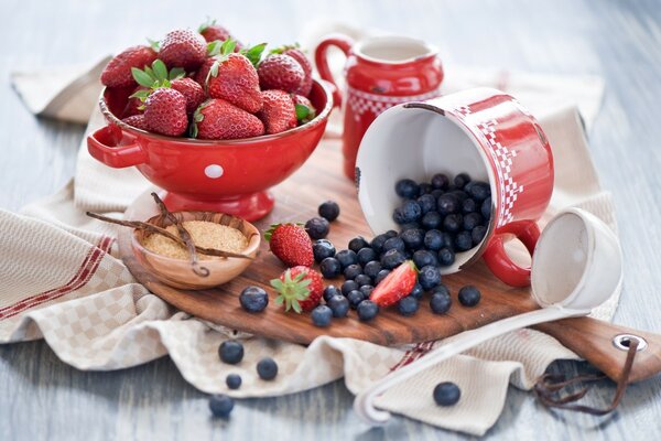 Taza con fresas, arándanos en el tablero