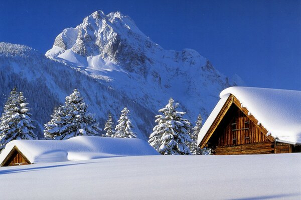 Roofs of houses in winter against the backdrop of majestic snowy mountains