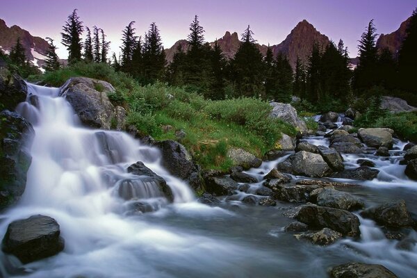 Waterfall among rocks and grass in the mountains