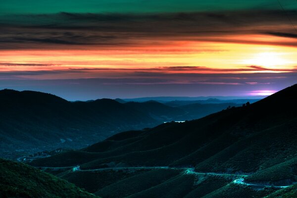 A hilly road leading into a beautiful sunset