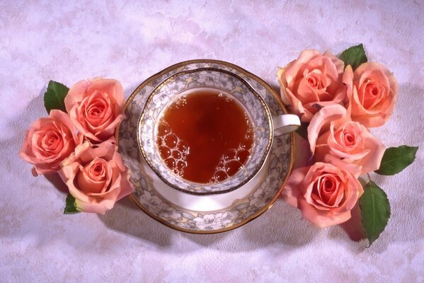 A cup of tea surrounded by pink roses