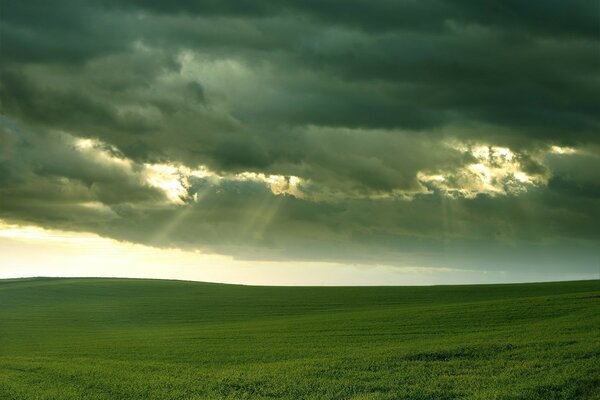 Vista del campo y los rayos del sol a través de las nubes